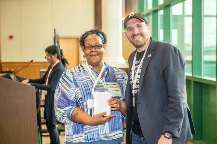 Jade Burnham and Andrew Coy accepting a 2024 Maryland Digital Equity Champion Award on behalf of the Digital Harbor Foundation